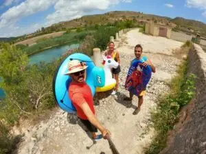 Three adventurers are taking a selfie with their rafts just before embarking on the white water rafting adventure Alicante