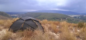 Wild camping up a mountain in a small green tent with views of Anna and Chella